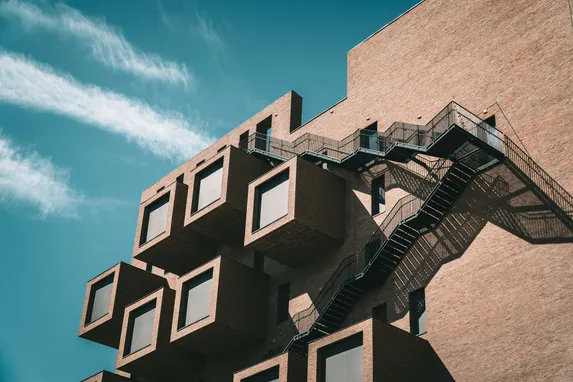 Moderne leilighetsbygg med karakteristiske kubiske balkonger og branntrapp mot blå himmel